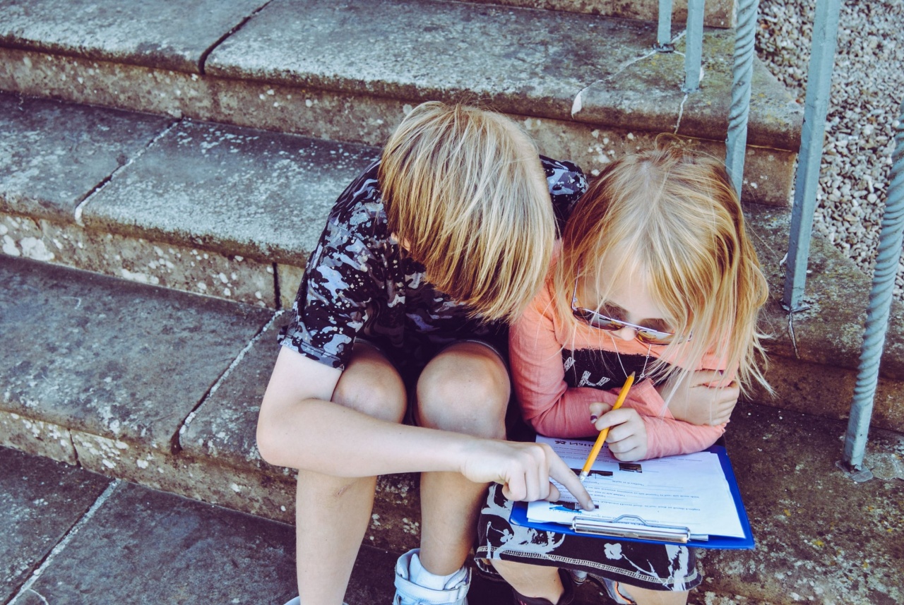 Zdjęcie, na którym jest dwoje dzieci siedzi na schodach nad książką lub zeszytem