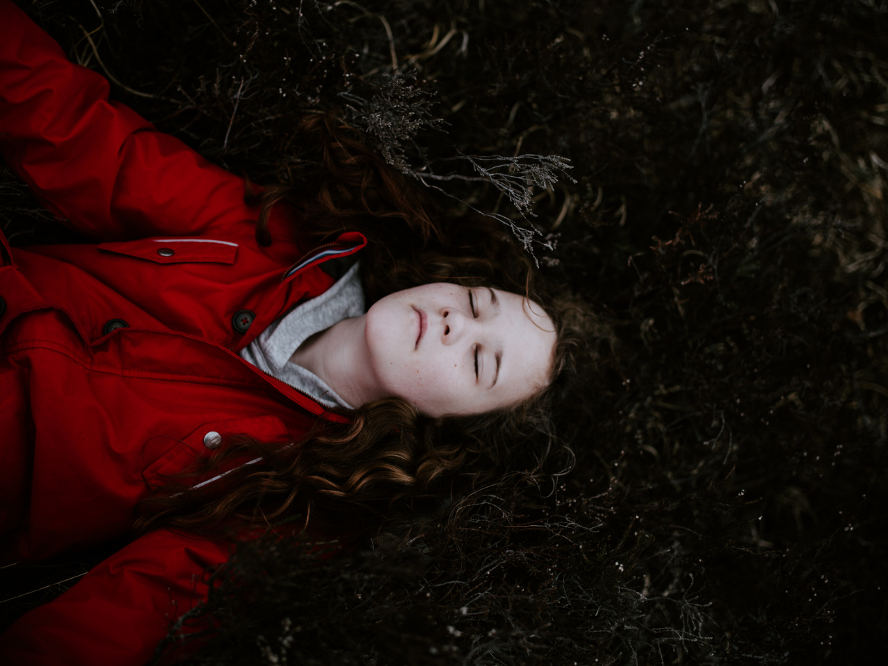 Dziewczynka leżąca na leśnej ściółce, z zamkniętymi oczami
