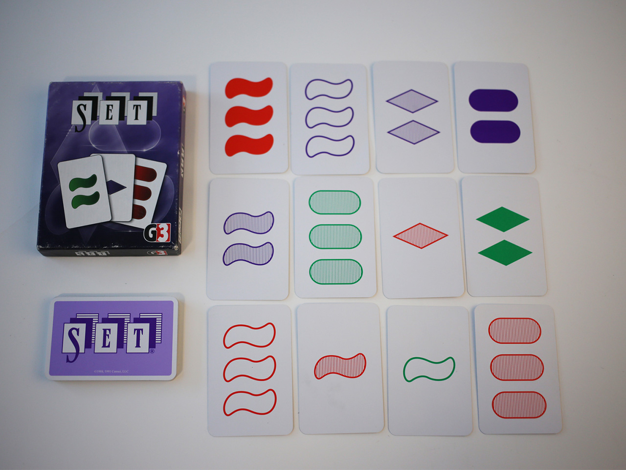 Zdjęcie, na którym jest pudełko i karty do gry SET